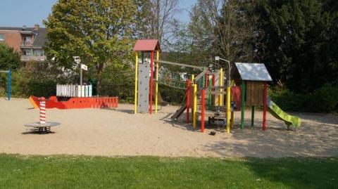 Ein Kinderspielplatz mit Kletterturm, Hängebrücke und einem nachgebildeten Schiff.