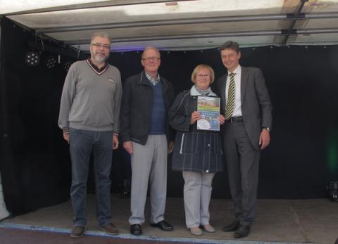 Bürgermeister Harald Lenßen (re.) und Franjo Terhart (li.) übergeben Dieter und Marianne Peun die Gewinnurkunde.